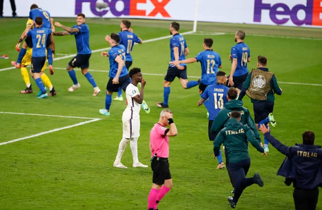 Italy players run past Saka to celebrate after his saved penalty. Image: PA Images