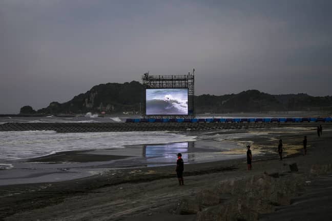 A giant screen displays the third round of men's surfing competition at the 2020 Summer Olympics, Monday, July 26, 2021, at Tsurigasaki beach in Ichinomiya, Japan. (Credit: PA)