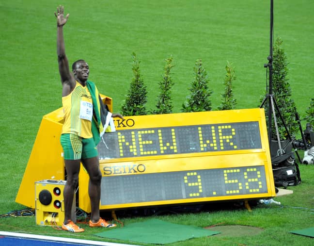 Bolt poses next to the screen showing his world record time. Credit: PA