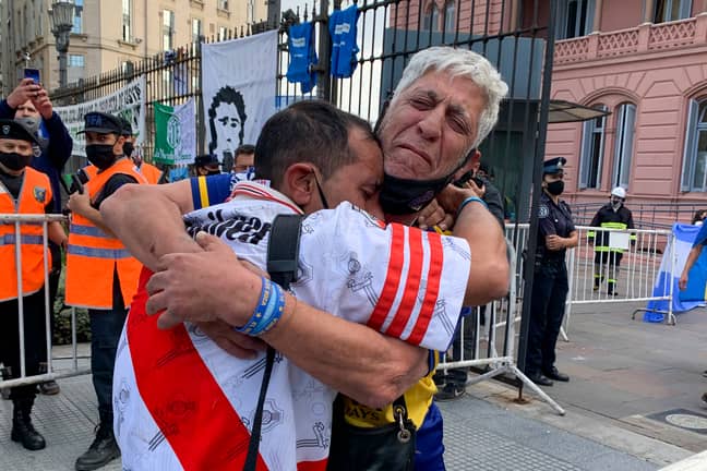 A Boca fan and a River Plate fan embrace as they mourn Maradona's death. Image: PA 